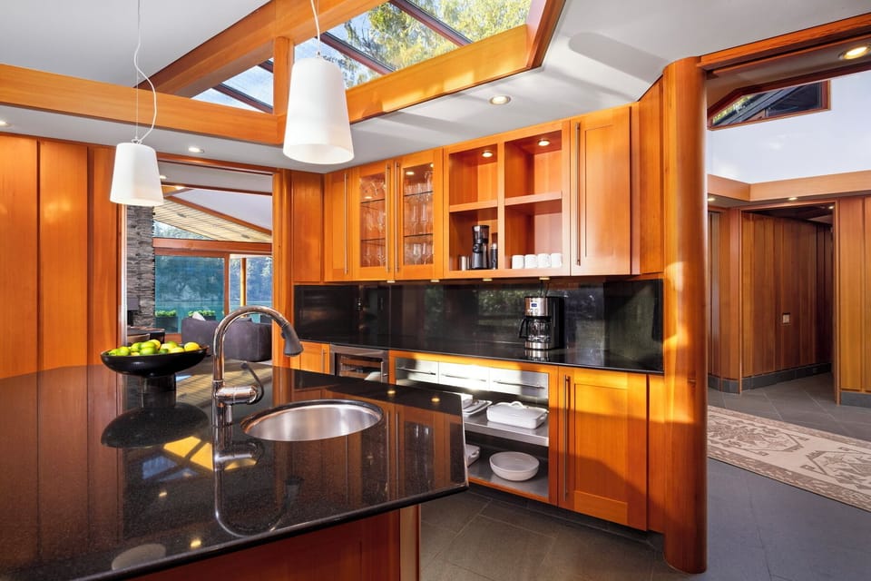 Your gourmet kitchen gleams with rich wood cabinets and granite counters, crowned by skylights that flood the space with natural warmth.