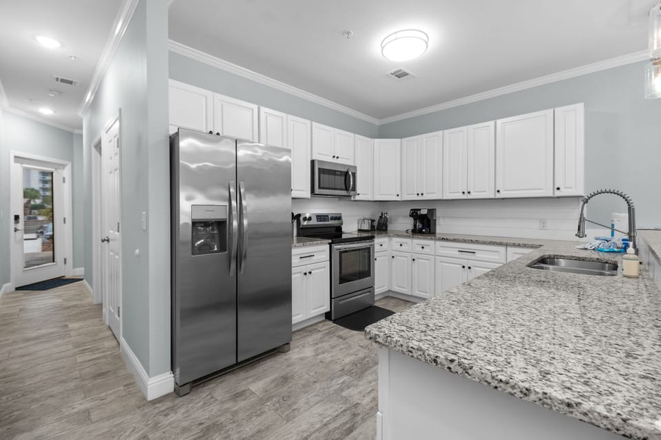 Fully equipped kitchen at Pescador Landing, Perdido Key – stainless steel appliances, granite countertops, and white cabinetry. Everything you need for home-cooked meals between trips to FloridaBama.
