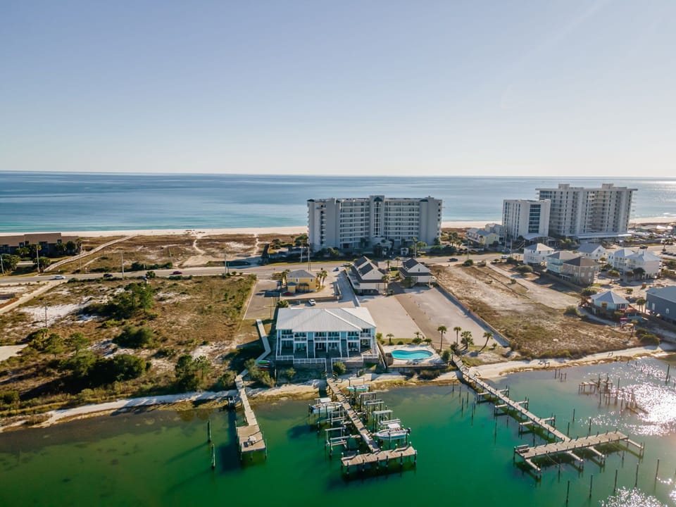 Bird's-eye aerial view of Pescador Landing in Perdido Key, FL – showing the private pool, marina, and Gulf of Mexico just steps away. Located near FloridaBama with stunning coastal scenery.