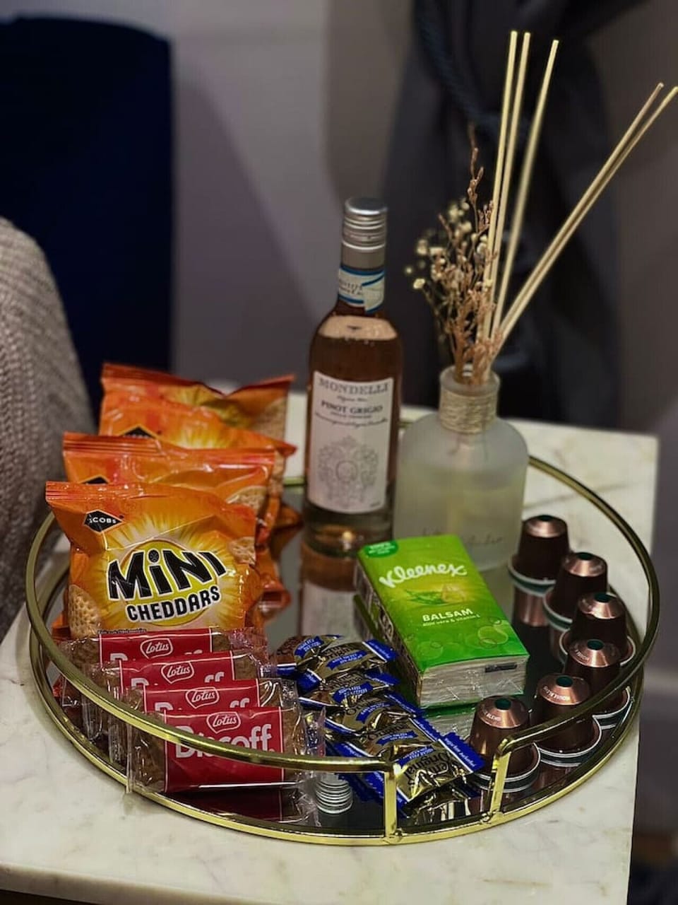 A welcome tray set up with snacks, drinks, and home fragrance on a side table.