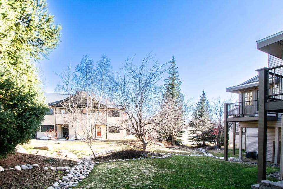 The tranquil exterior showcases a well-maintained garden with stone walkways and towering trees, creating a peaceful retreat amidst the vibrant Steamboat Springs landscape.