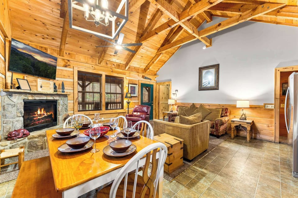 Gather around a rustic wooden table for 6, set beside a cozy stone fireplace.
