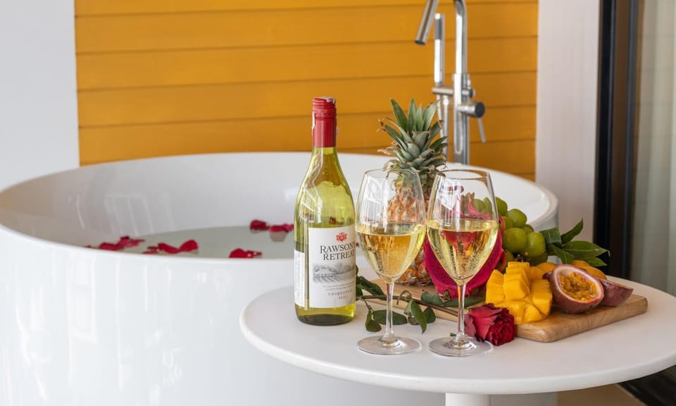 Elegant bathtub setup with wine and fruit for a relaxing experience.