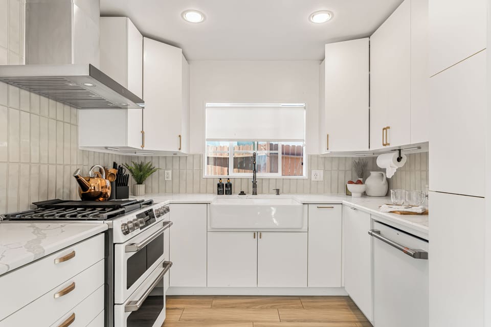 Full view of the bright, modern kitchen with white cabinetry and stainless steel appliances