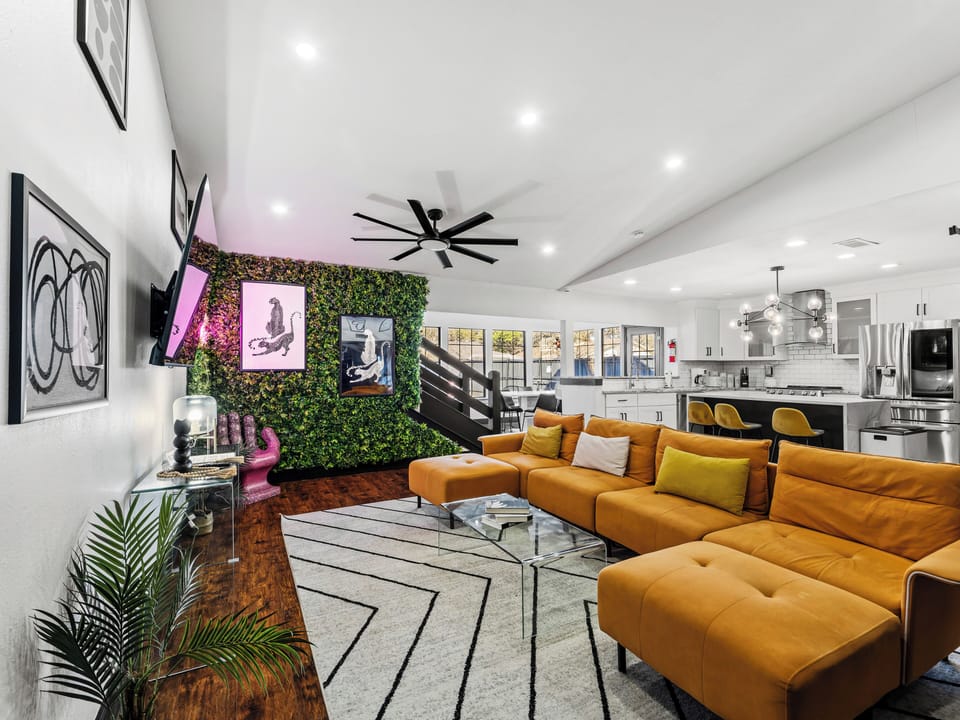 Settle into this vibrant living space where modern art meets comfort. Your plush orange sectional faces a stunning living wall, creating the perfect backdrop for relaxation.