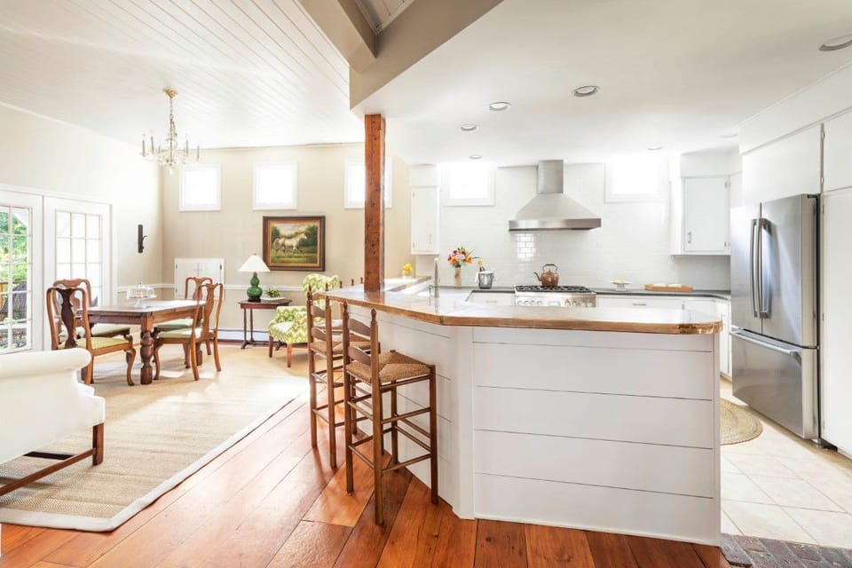 An open-concept kitchen and dining area combines functionality and style, featuring a central island and warm natural light from large windows.