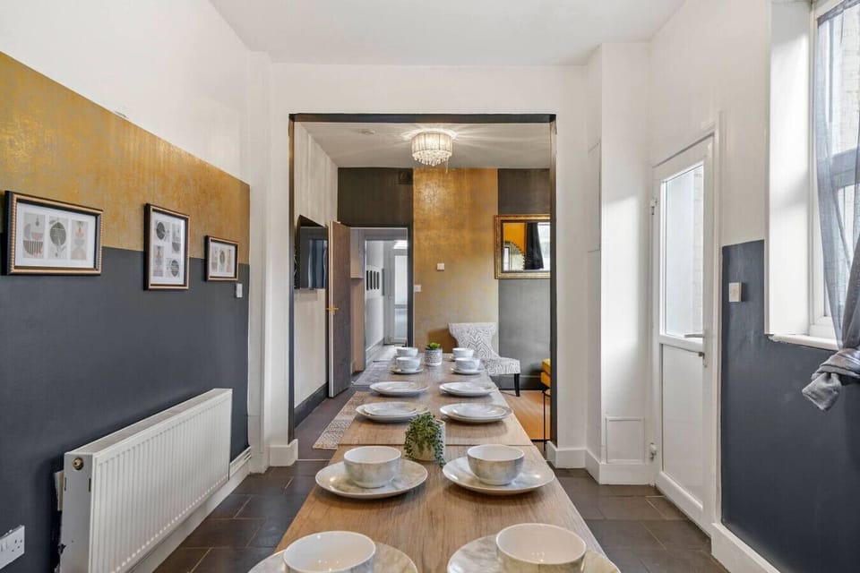 Long dining table laid with place settings and a clear view through to the kitchen.