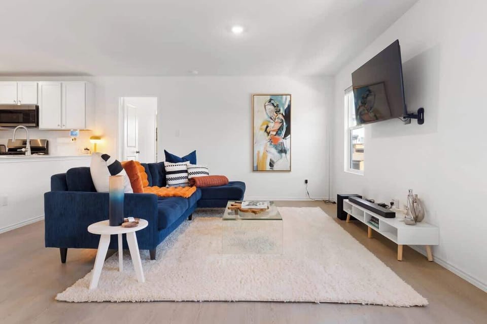 Spacious living room with a cozy navy sectional, bright natural light, and a 55” TV for streaming your favorite shows. This open-concept space flows into the kitchen and dining areas, creating the perfect place to unwind, gather, and relax.
