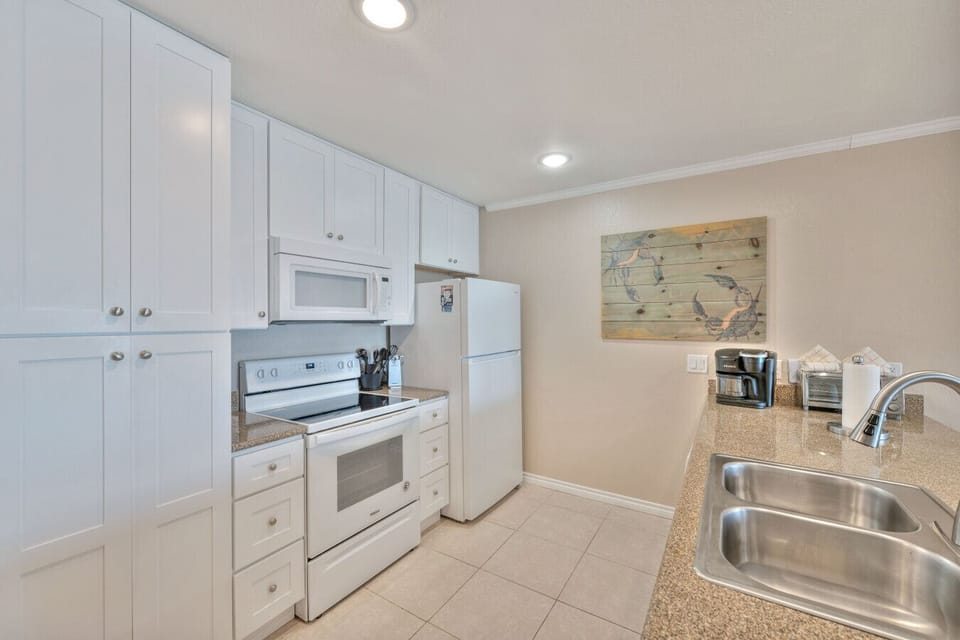 Fully equipped kitchen with white cabinetry and granite countertops