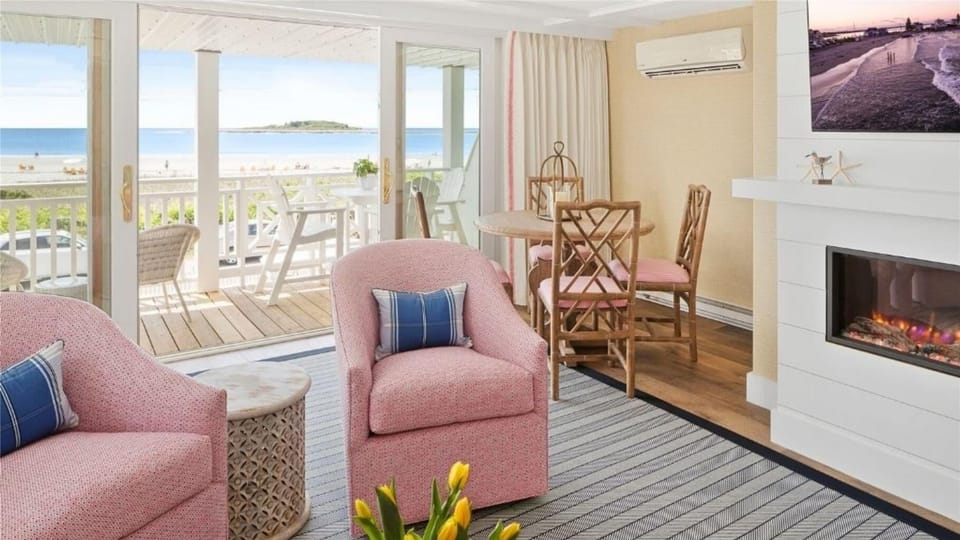 Enjoy stunning ocean views from the cozy living space, featuring pink chairs and a stylish fireplace, perfect for relaxation.