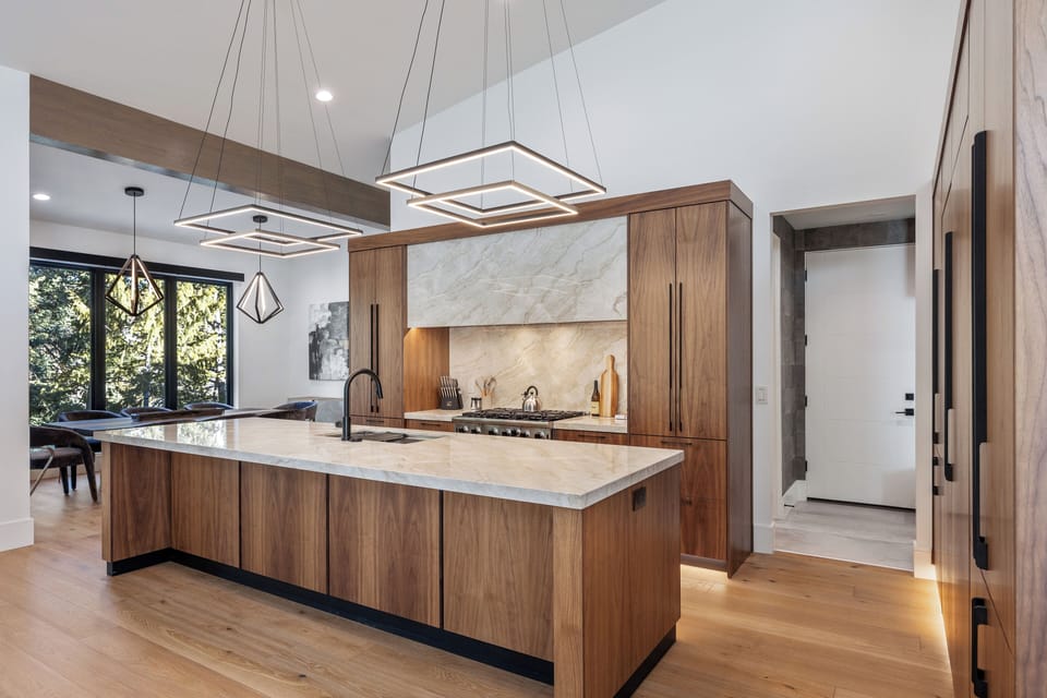 Stunning main-floor kitchen showcasing an oversized island, premium finishes, modern appliances, and ample workspace—ideal for cooking, entertaining, and shared meals.
