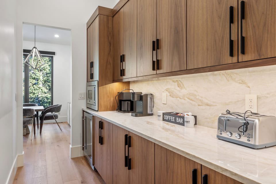 Convenient main-floor coffee and prep area with generous counter space, cabinetry, and small appliances—perfect for morning coffee or extra serving space when entertaining.
