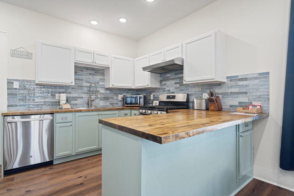 Coastal chic kitchen with a spacious butcher-block island, stainless appliances, and everything you need to cook at home.