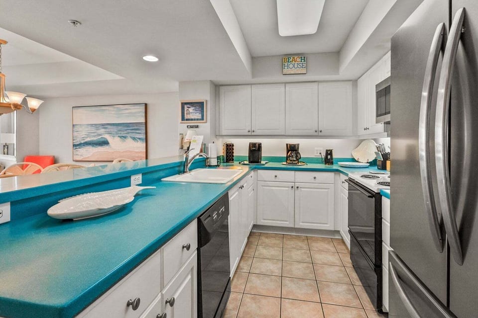 Kitchen with blue counters, white cabinetry and full-size appliances at Ocean Bay Club 107, Ocean Drive