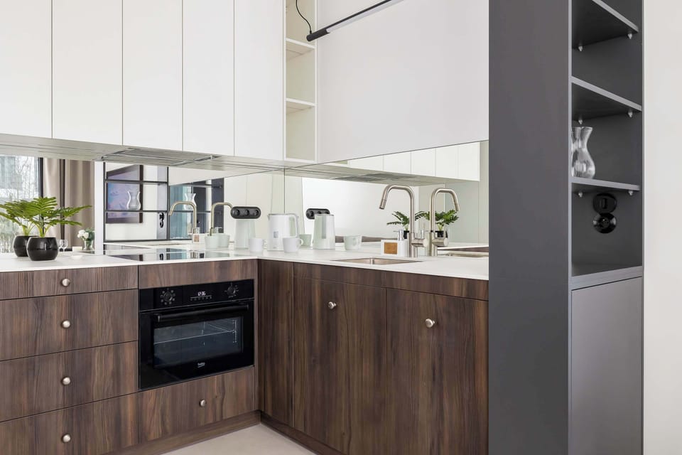 Modern kitchenette with wood-finish cabinets and clean countertop workspace.