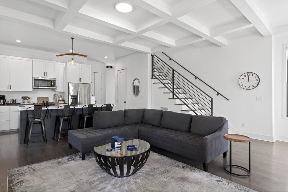 Living room view highlighting the sleek black metal staircase and open floor plan