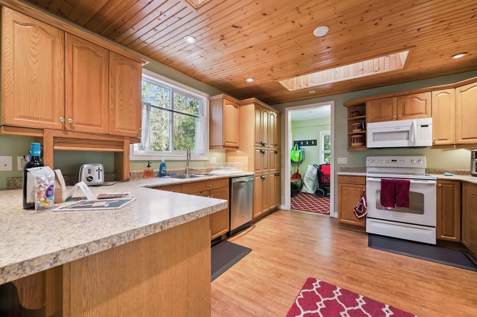 Bright kitchen workspace with lots of cabinets, a dishwasher, and an easy flow into the rest of the cottage.