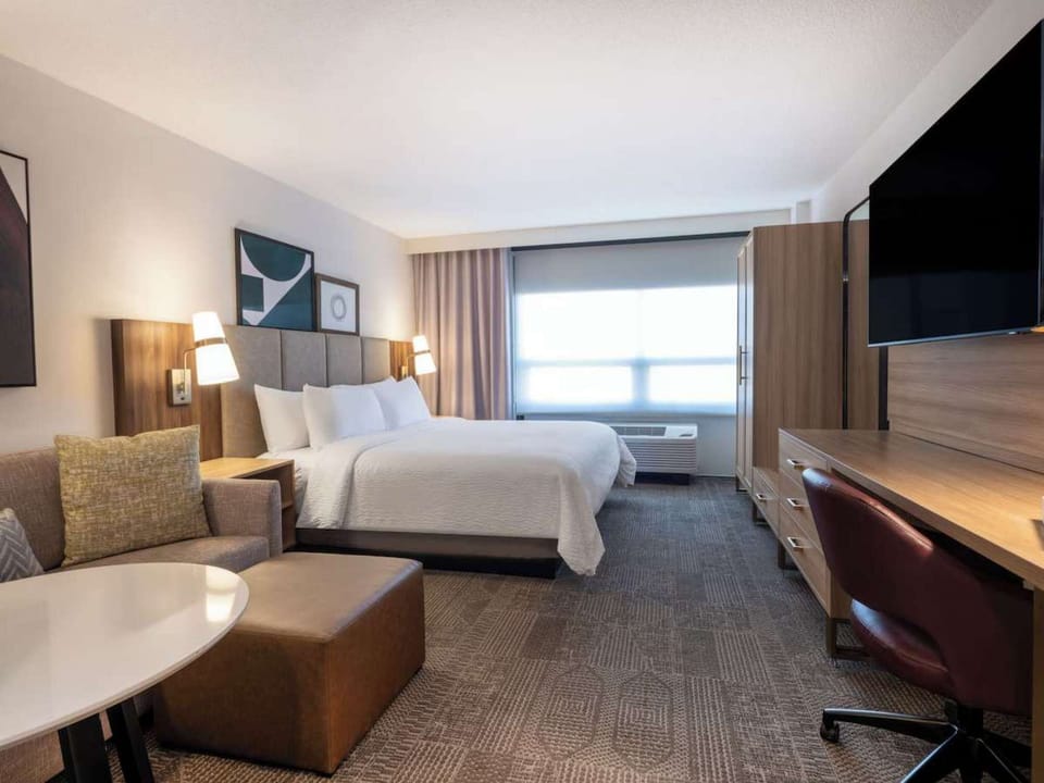 Wide room view with king bed, desk, TV, and seating space