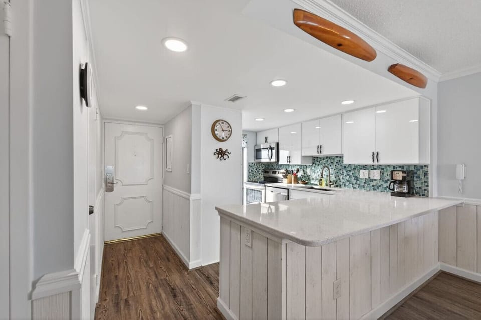 Bright, open kitchen with a large island, white cabinetry, and modern finishes. Thoughtful layout offers plenty of space to cook, gather, and enjoy a relaxed coastal stay.