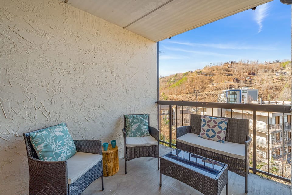 Your private balcony offers comfortable seating with soft cushions and decorative pillows, perfect for morning coffee while enjoying hillside views.