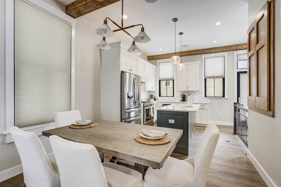 The airy living space features soaring ceilings with rustic wood beams. This open floor plan connects the seating area to the dining room and kitchen, creating a perfect environment for social gatherings and relaxation during your stay.