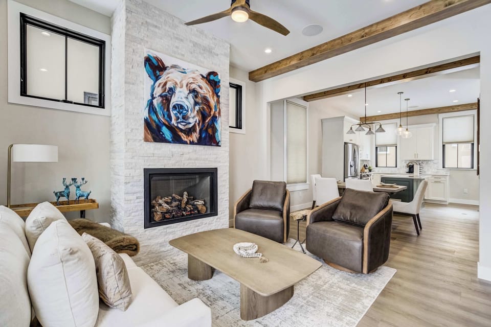 Welcome to Frontier Post! This stunning living area features a modern fireplace and striking bear artwork as a central focal point. The open floor plan flows seamlessly into the gourmet kitchen making it a perfect gathering spot for your group.