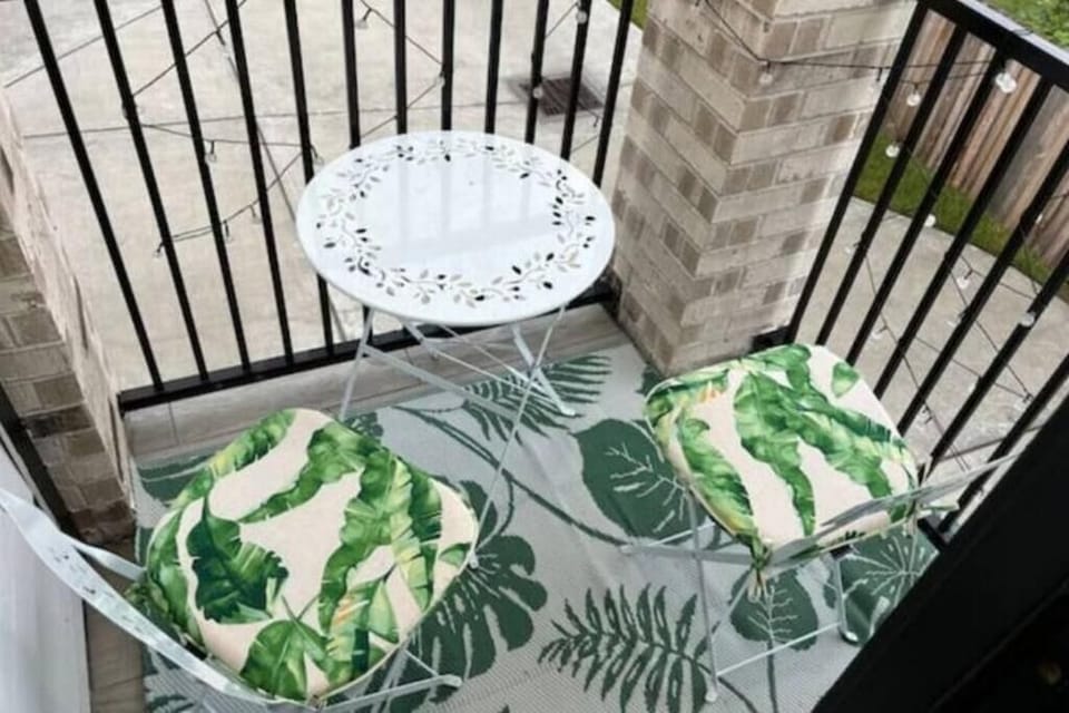 Chic balcony retreat with tropical accents, cozy seating, and a relaxing vibe.