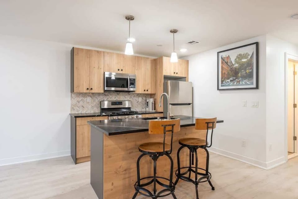 Modern open kitchen with full-size stainless appliances and a functional island for quick meals or morning prep before heading into the city. Clean finishes and efficient layout make everyday living easy.