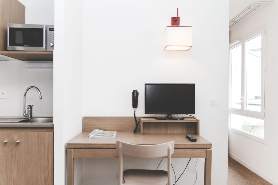 A practical desk sits beside the kitchenette, offering a bright space for work or planning the day.
