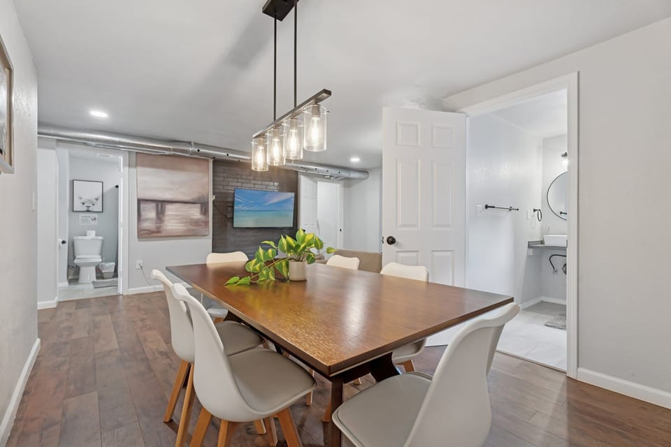 Stylish dining room with seating for six, modern pendant lighting, and abstract art—perfect for meals or remote work.