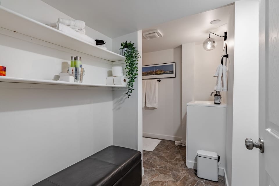 Bathroom with walk-in shower, towels, and open shelving for personal items.
