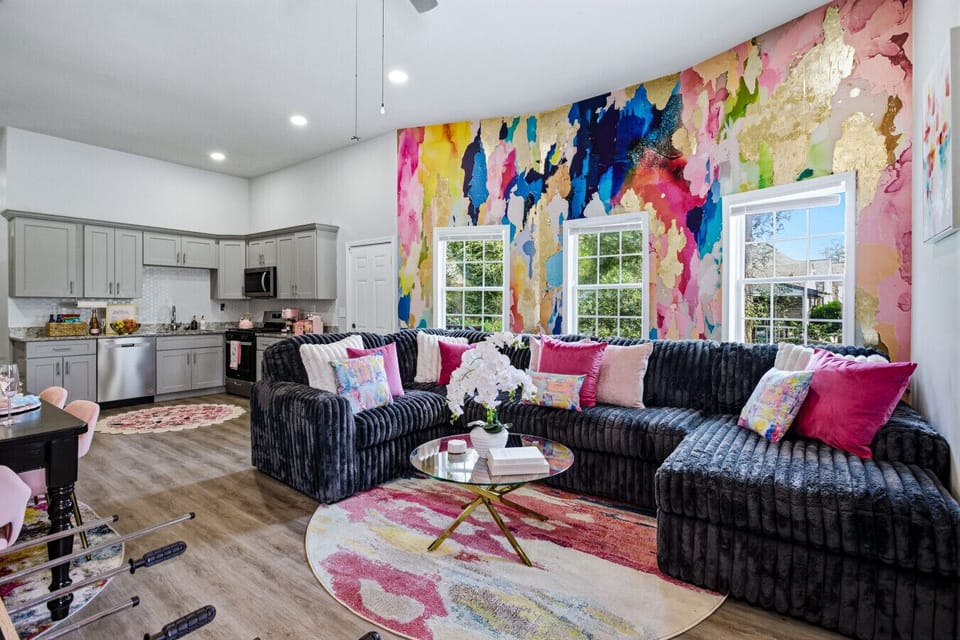 Cozy living room with plush seating, watercolor accent wall, and soft pink details