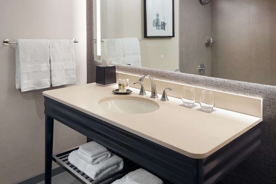 Sink area with bright mirror, towels, and bath essentials