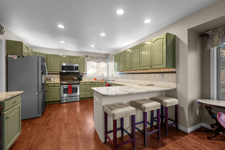 Sunny kitchen with granite countertops, modern appliances, and breakfast bar seating.Evening curb view showcasing the home's inviting exterior and well-lit entryway.