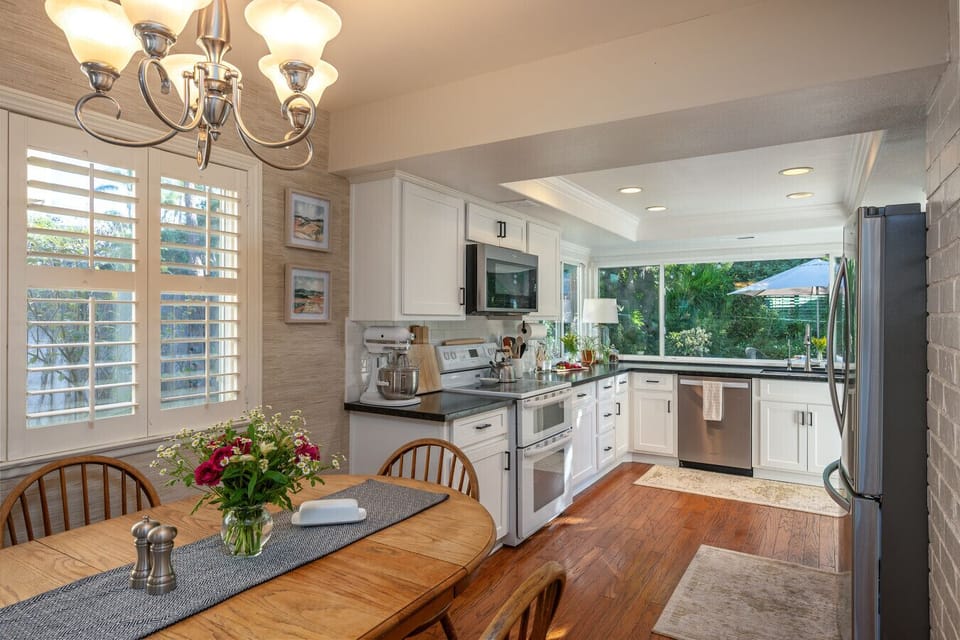 Open dining and kitchen layout with warm wood flooring, updated cabinetry, and abundant natural light. A bright, inviting space designed for easy daily living and effortless entertaining.