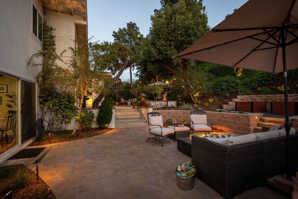 Inviting backyard retreat with layered patio seating, ambient lighting, and a warm fire feature. Ideal for evening gatherings and relaxed outdoor living.