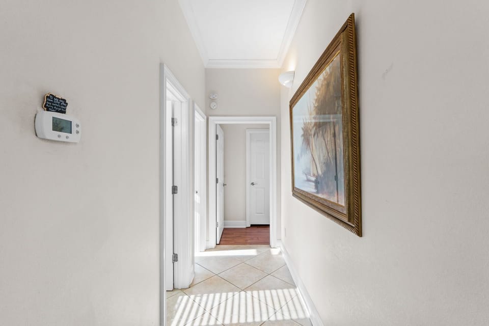 Step into your bright, welcoming hallway where coastal artwork and clean white doors guide you to your comfortable retreat spaces.