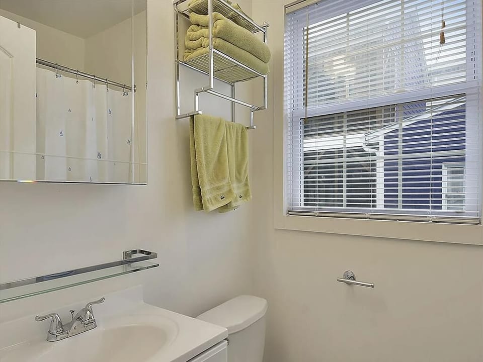 Bright bathroom with a glass shelf, neatly arranged towels, and a large window for natural light.