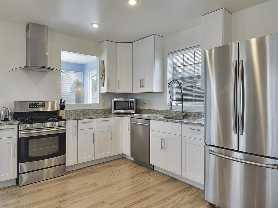Well-equipped kitchen with double sink, gas stove, and built-in appliances set in white cabinetry.
