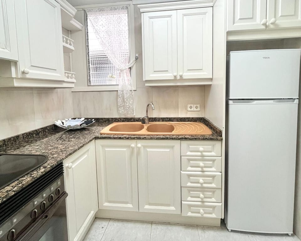 Fully equipped kitchen in Apartment Gola featuring white cabinetry, granite worktop, oven, hob and fridge, bright and practical.