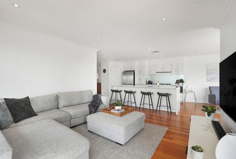 Spacious open-plan living area with comfy sectional and kitchen island seating. Enjoy watching TV with family!