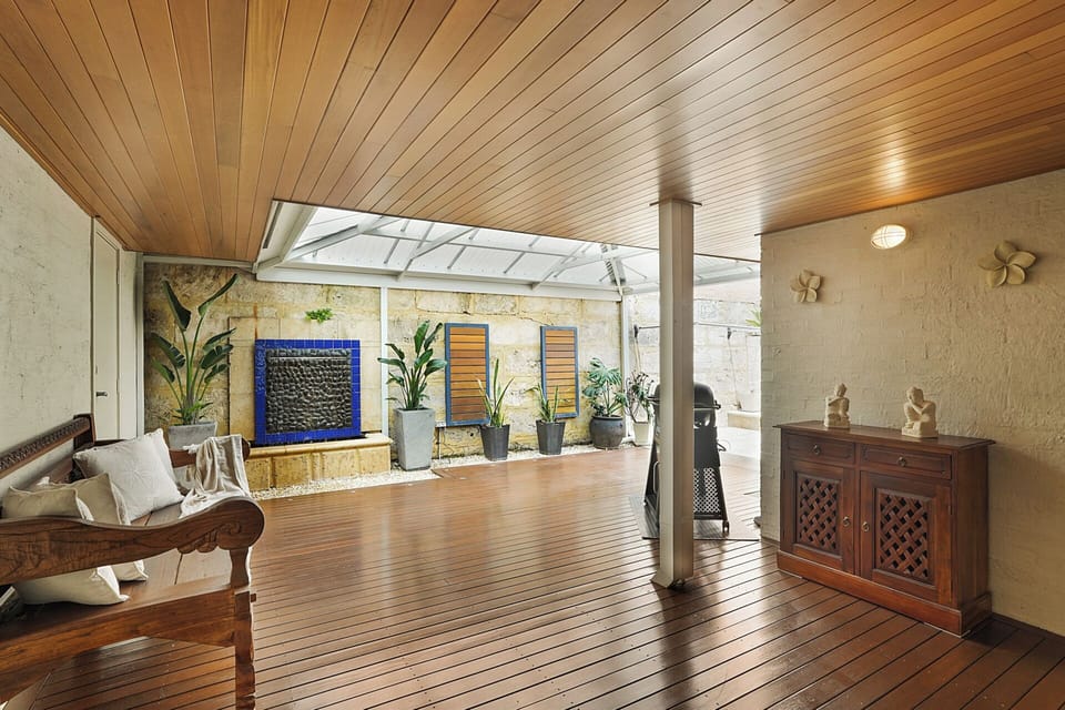 Private covered patio with wooden deck, BBQ, and tranquil water feature—perfect for relaxation