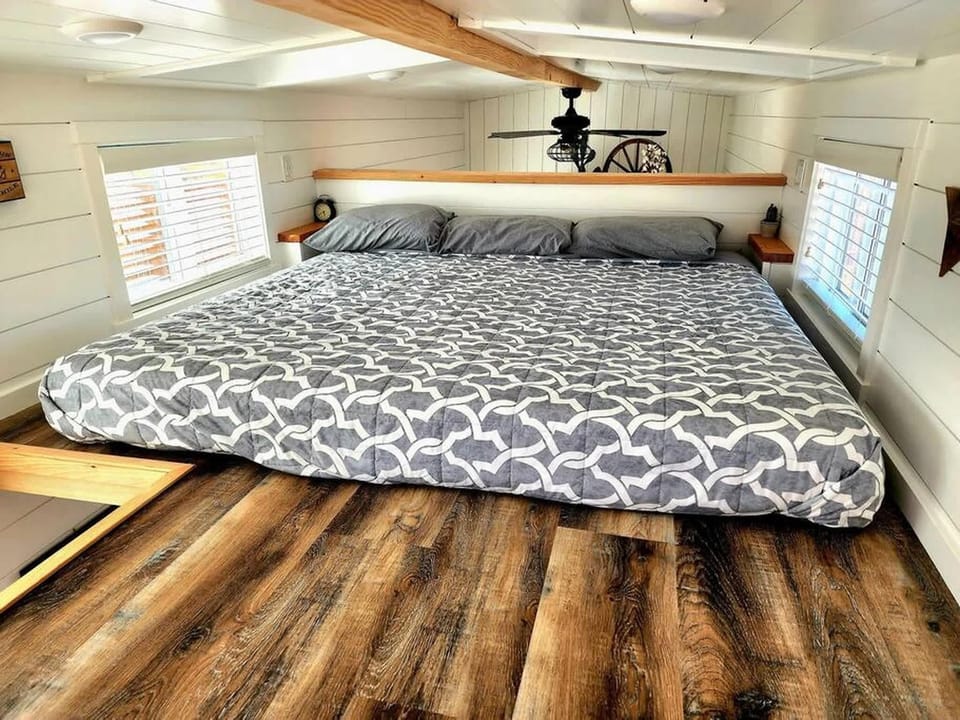 Comfortable king bed in a cozy loft sleeping area with low-profile windows and warm wood finishes. Bright, inviting space designed for restful nights after exploring Southern Utah.