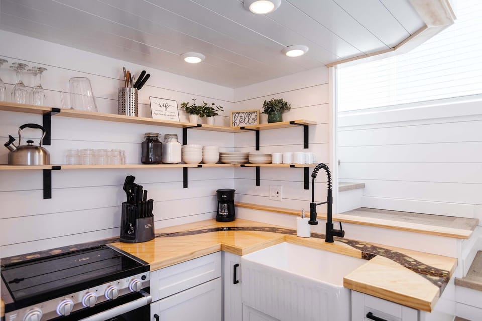 Bright tiny home kitchen with warm wood countertops, open shelving, and a farmhouse sink for an inviting place to prepare meals.