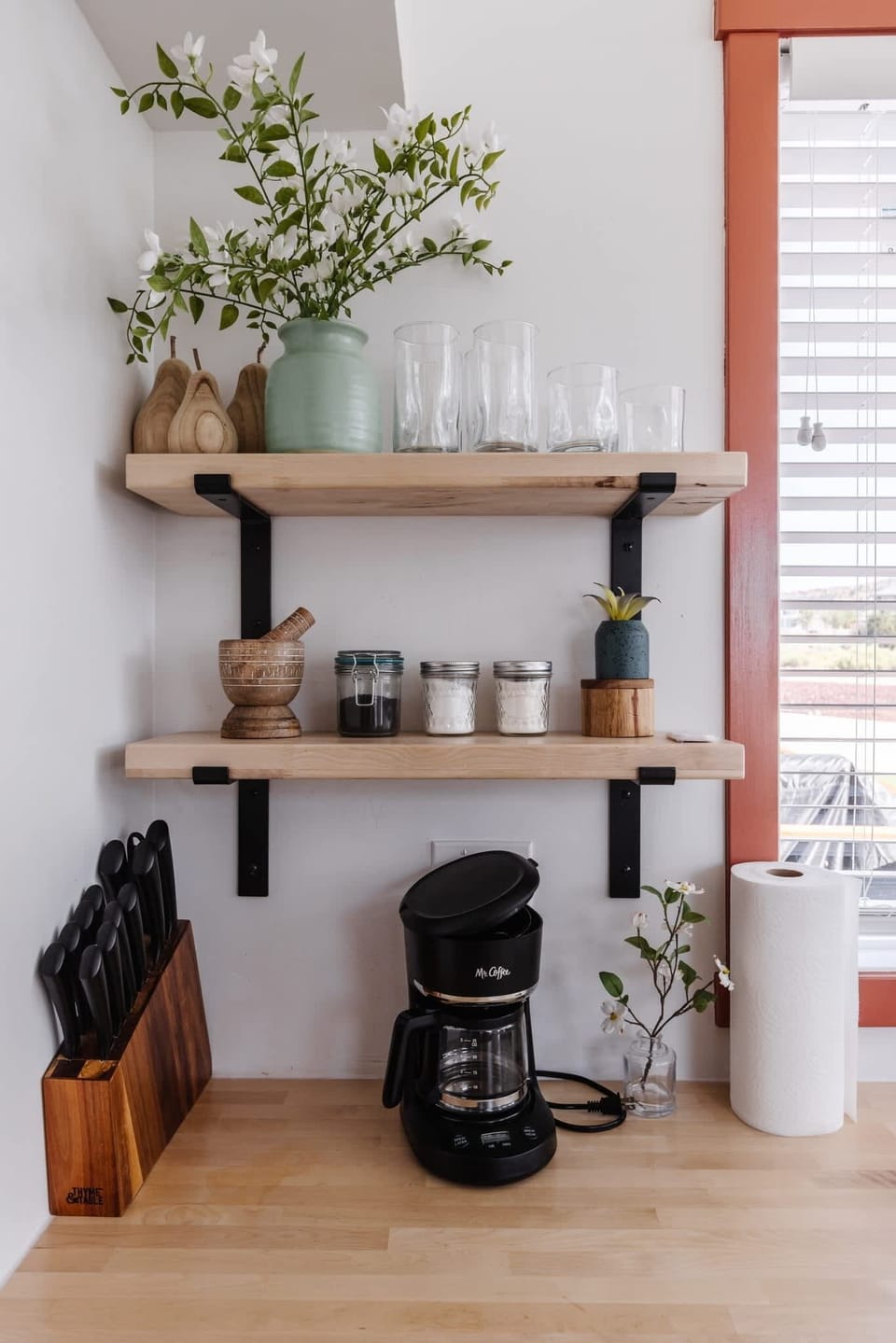 Start your day at the dedicated coffee station featuring a drip coffee maker, mugs, glassware, and convenient open shelving. Everything is within easy reach for your morning routine.