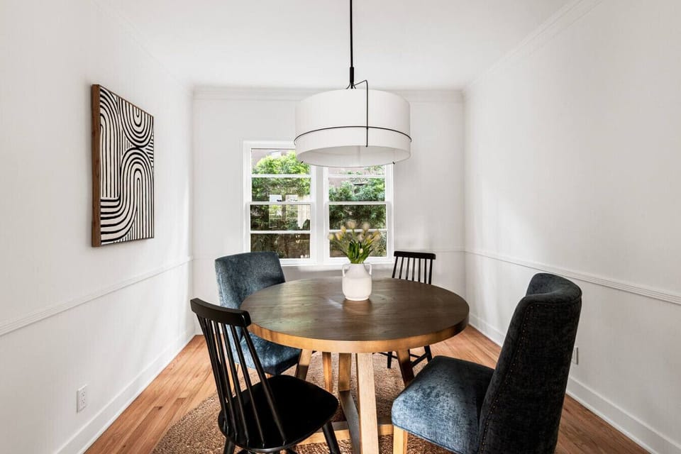 Warm wooden dining table illuminated by a large, modern white light fixture.