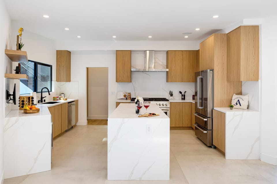 A sleek, chef-style kitchen with a spacious waterfall island, modern appliances, and seamless flow to indoor-outdoor living—perfect for cooking, gathering, and entertaining.