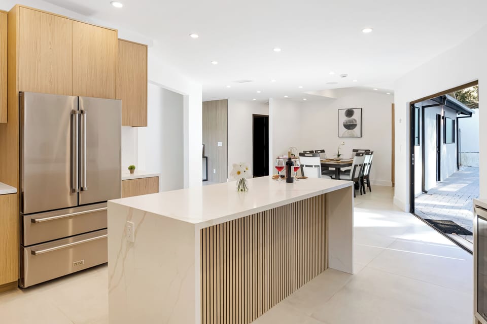 A sleek, chef-style kitchen with a spacious waterfall island, modern appliances, and seamless flow to indoor-outdoor living—perfect for cooking, gathering, and entertaining.