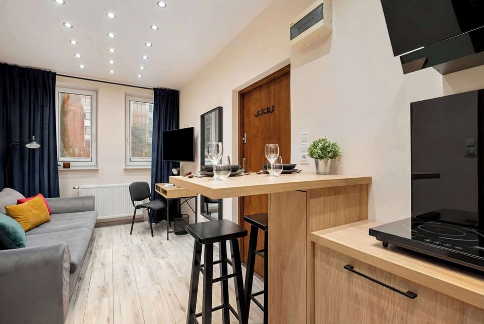 An open-plan living area connecting the kitchen and seating space. A bar counter with stools separates the zones. The room feels modern and well-organized.