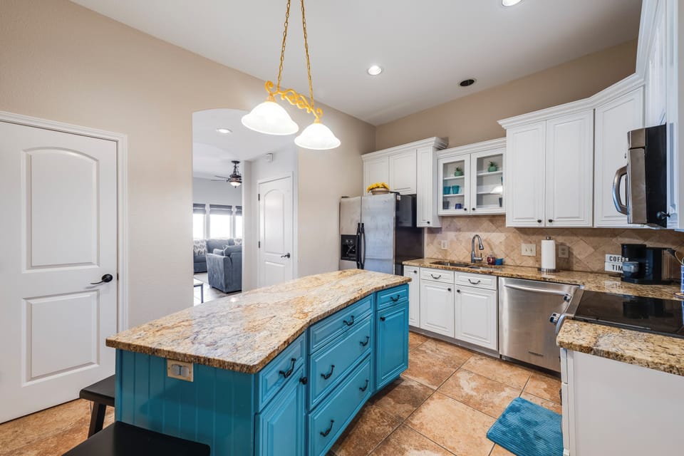 Your spacious kitchen features granite countertops, modern appliances, and a stunning turquoise island perfect for preparing memorable meals together.